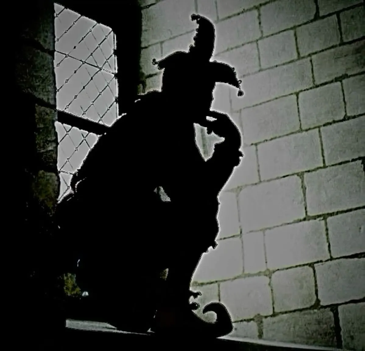 Jester silhouette crouched in a castle window